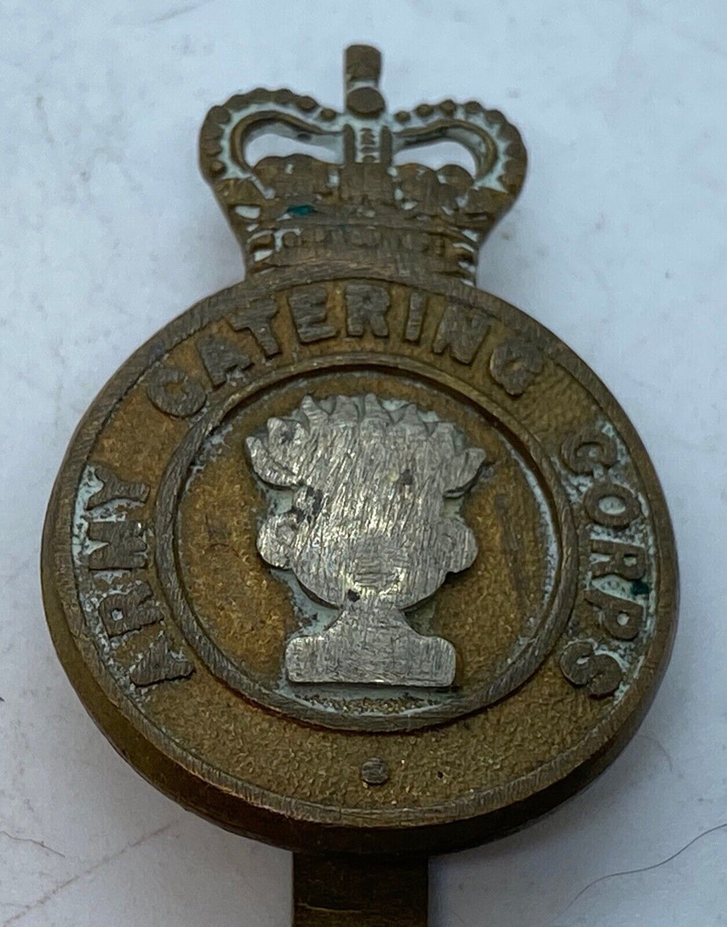 A worn Queens crown ARMY CATERING CORPS cap badge with rear slider -- -- B36 - The Militaria Shop